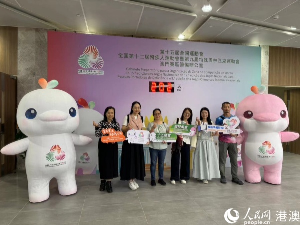 图为参加培训的澳门赛区部分志愿者在倒计时牌前，与赛事吉祥物合影。人民网记者 富子梅摄